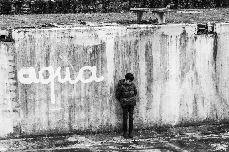 enfant dans une piscine vide avec graff Aqua sur le mur