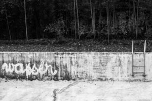 piscine vide avec graff allemand sur le mur